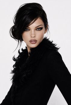 Woman with dark hair and smoky eyes wearing a black jacket with a fur collar