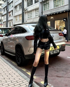 Woman with long black hair in a leather outfit standing on a city street