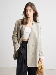 Woman in an oversized blazer and crop top holding a straw bag