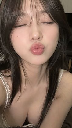 Woman with closed eyes and pursed lips, showing cleavage in a lace top