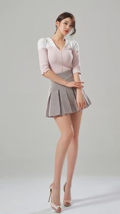 Woman in a pink top and pleated skirt posing in a studio