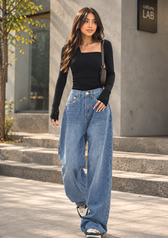 Woman with long hair wearing a black top and baggy jeans walking outdoors