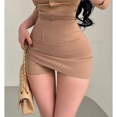 Woman in a beige high-waisted skirt and top holding a handbag