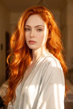 Woman with long red hair and green eyes in a light blue robe with lace trim