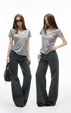 Two women in gray t-shirts and wide leg jeans posing in a studio