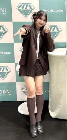 Woman in a brown blazer and shorts posing indoors