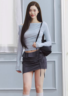 Woman in a light blue crop top and dark mini skirt with a shoulder bag