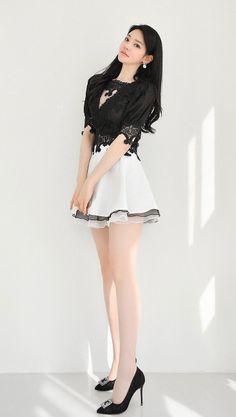 Woman in a black lace top and white skirt posing indoors