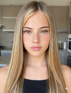 Young woman with long blonde hair and green eyes in an indoor setting