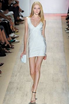 Blonde model in a white dress walking on a runway