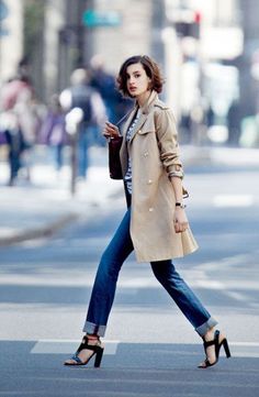 Woman in a trench coat and jeans crossing a street