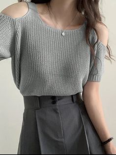 Woman wearing a light gray knitted off-shoulder top and dark gray pants