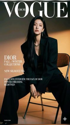 Woman in a black suit and jewelry sitting on a chair indoors