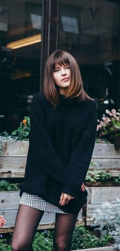 Woman in a black turtleneck sweater and plaid skirt outdoors