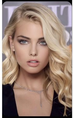 Blonde woman with blue eyes and a necklace, looking directly at the viewer