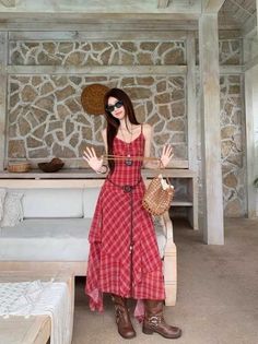 Woman in a red plaid dress, sunglasses, and brown boots indoors