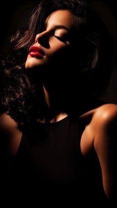 Woman with red lipstick and closed eyes in dramatic lighting