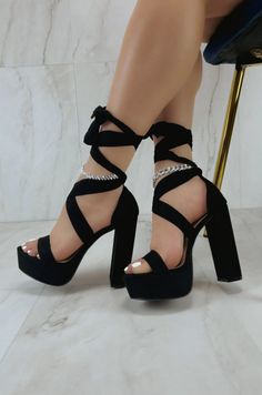 Woman wearing black platform high heels with rhinestone anklets on a marble floor