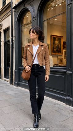 Woman in a brown jacket and black jeans walking on a street