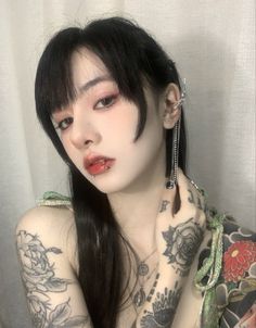 Woman with long black hair, lip piercing, and tattoos on her arms and shoulder