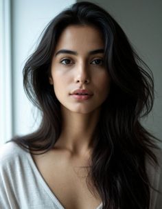 Woman with long dark hair wearing a v-neck shirt, looking directly at the camera