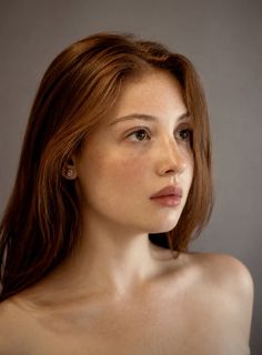Woman with red hair and freckles looking away in a studio portrait
