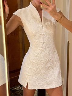 Woman in a white textured dress taking a mirror selfie