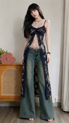 Woman in a floral top, wide leg jeans, and a belly chain posing indoors