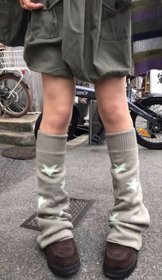 Person wearing leg warmers with star patterns and brown shoes on a street