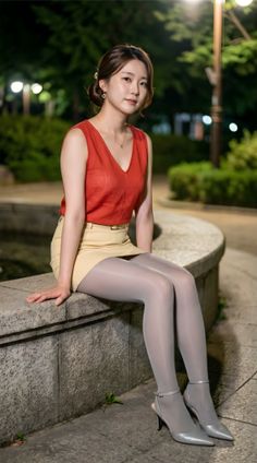 Woman in a red top and mini skirt sitting outdoors at night
