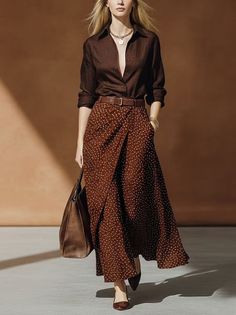 Woman in a brown shirt and polka dot skirt with a brown bag