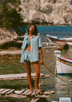 Woman in a bikini top and matching shorts set standing on a wooden pier