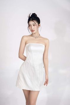 Woman in a white strapless dress with an updo hairstyle posing in a studio