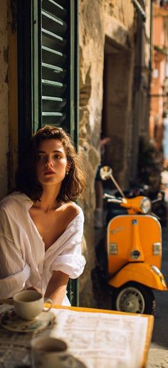 Woman in a white shirt at an outdoor cafe with an orange scooter in the background
