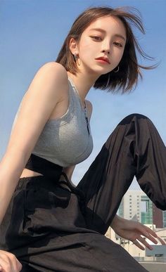 Woman in a grey tank top and black pants against a blue sky