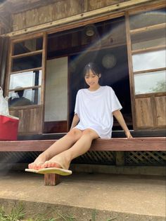 Young woman in a white t-shirt sitting on a wooden porch