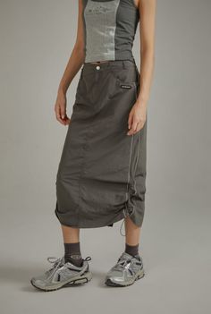 Person wearing a gray sleeveless top and a drawstring midi skirt with athletic shoes