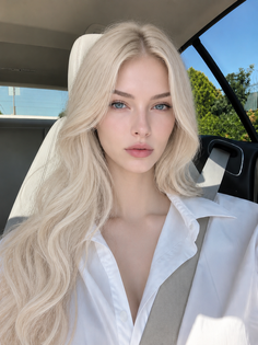 Woman with long blonde hair and blue eyes in a white shirt inside a car