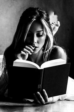 Woman with long hair reading a book in black and white