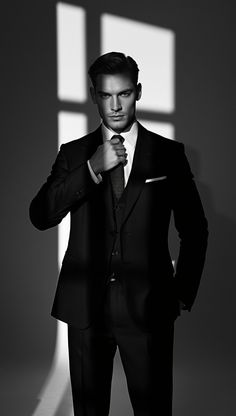 Man in a suit adjusting his tie with dramatic lighting and shadows