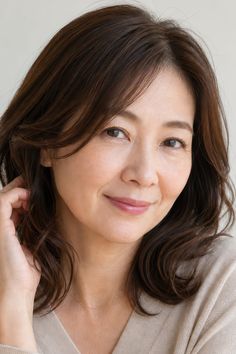 Woman with brown wavy hair and a subtle smile wearing a gold necklace