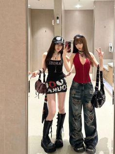Two women in alternative fashion posing for a mirror selfie indoors