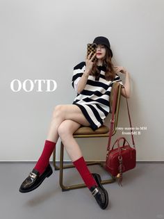 Woman in a striped dress, bucket hat, and red socks sitting indoors