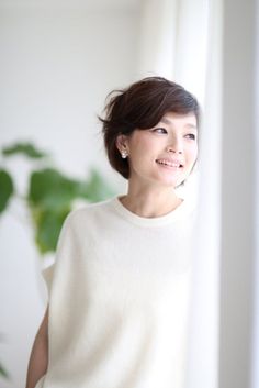 Woman with short hair and pearl earrings smiling indoors