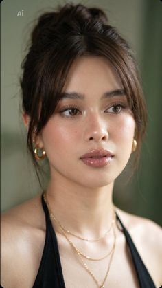 Woman with brown hair in a messy bun wearing gold jewelry