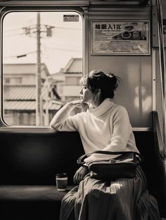 Woman in a turtleneck sweater and pleated skirt looking out a train window