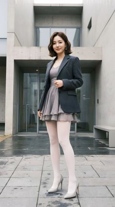 Woman in a blazer and mini dress with white tights and high heels outdoors
