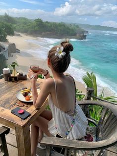 Woman with a frangipani flower in her hair, enjoying a meal with an ocean view