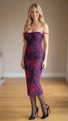 Woman in a purple floral dress and black high heels standing indoors