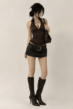 Woman in a dark halter top, mini skirt, and high heel boots posing in a studio